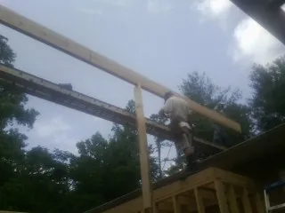 Carpenter setting a ridge beam over a new addition frame — Ice Dam Removal by Roofing Brothers in Hoyt