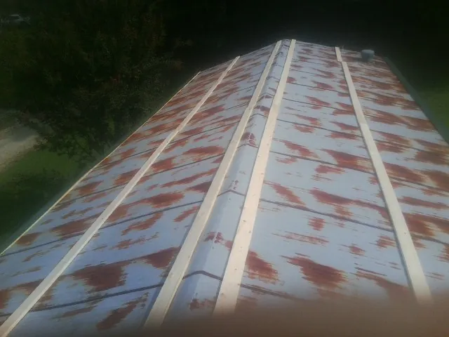 Rusted metal roof panels with new wood purlins before replacement — Storm Damage Roof Repair in Hoyt by Roofing Brothers