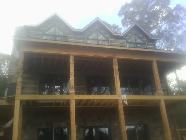 Dormers and porch framing on a large log home under construction — Roof Coating work by our crew in Hoyt