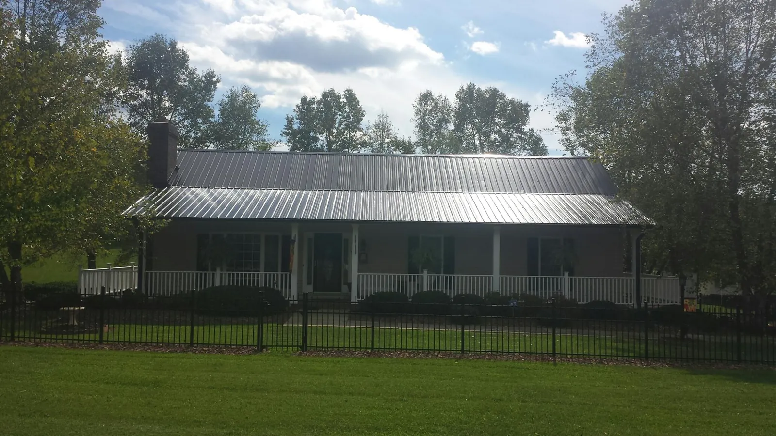 Gray metal roof on a brick ranch with a full width front porch — Gutter Guard Installation work by our crew in Hoyt