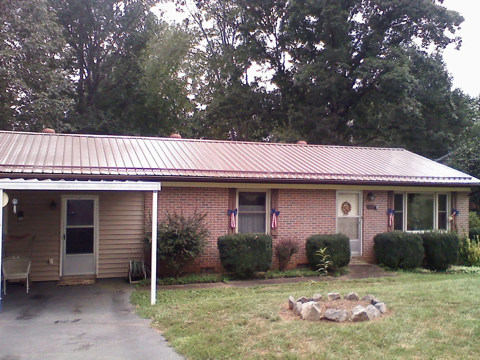 Bronze metal roof and carport on a brick ranch home — Roof Repair work by our crew in Hoyt