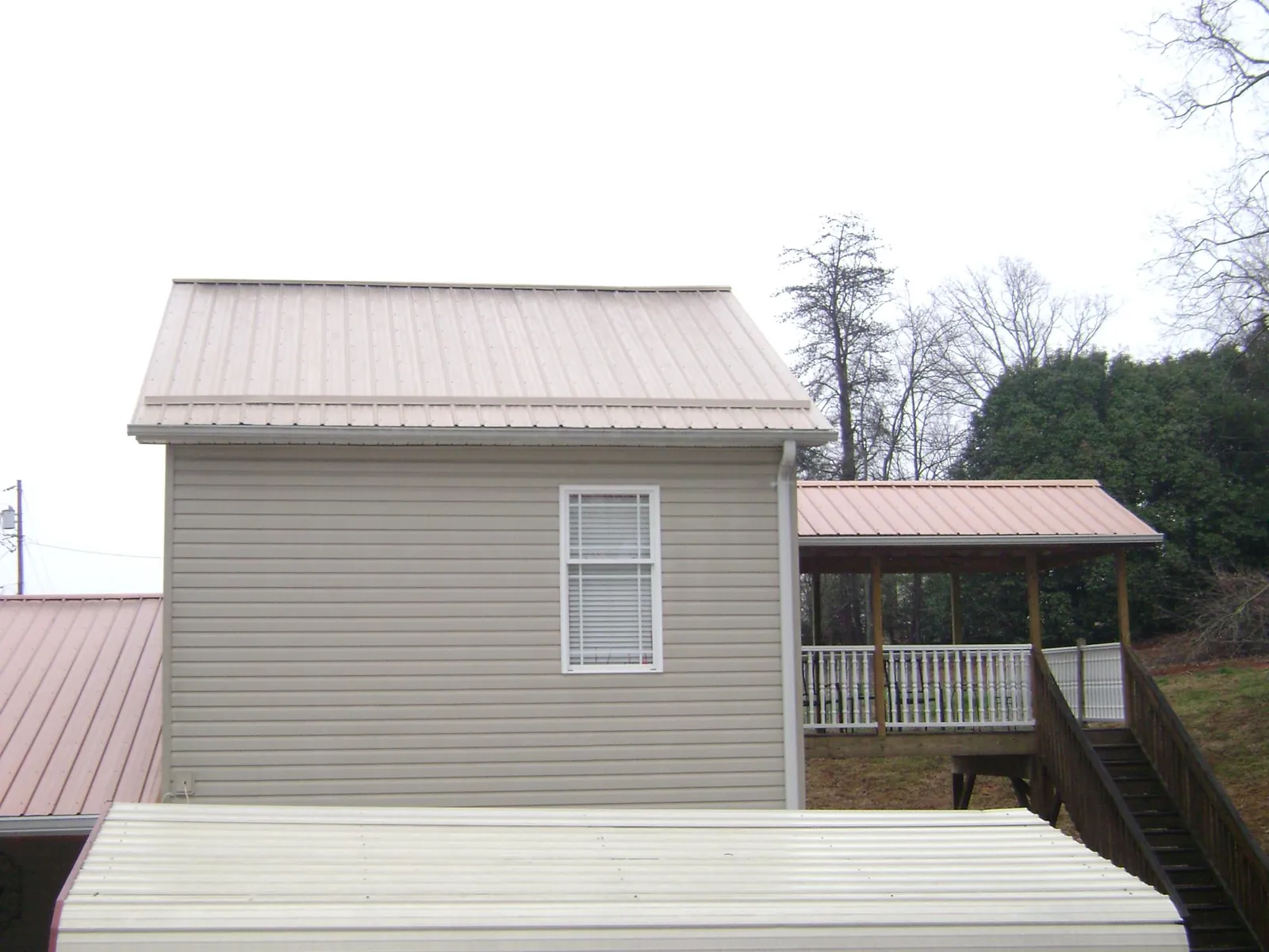 Tan metal roofs on a two story addition and attached porch, from a Roof Replacement job in Hoyt