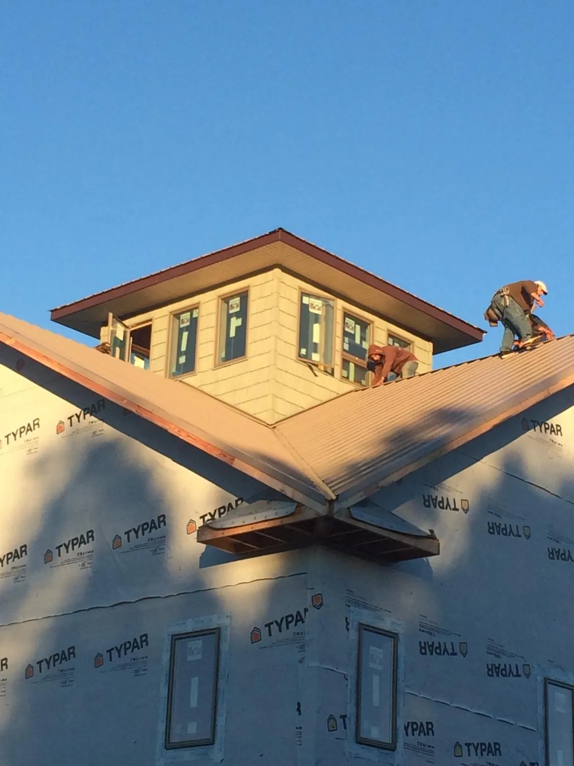 Roofers working around a rooftop cupola on a new metal roof at sunset — Roof Waterproofing in Hoyt by Roofing Brothers